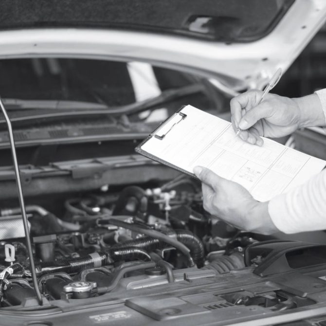 Mechanic engineer hand holding checklist paper and taking a note on clipboard with car engine background.